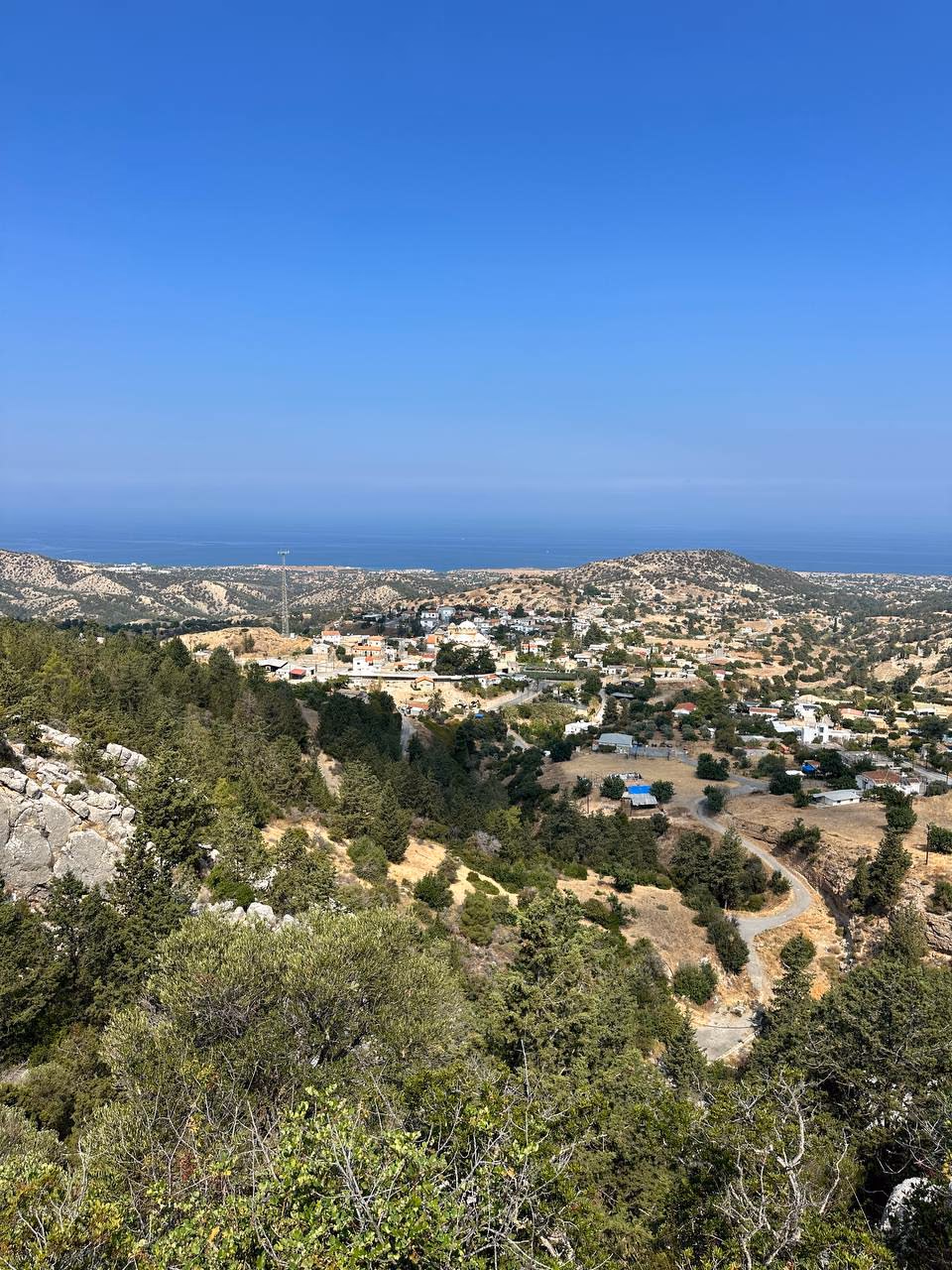 Çam ormanının üzerinden Tatlısu belde merkezi ve ufukta Akdeniz