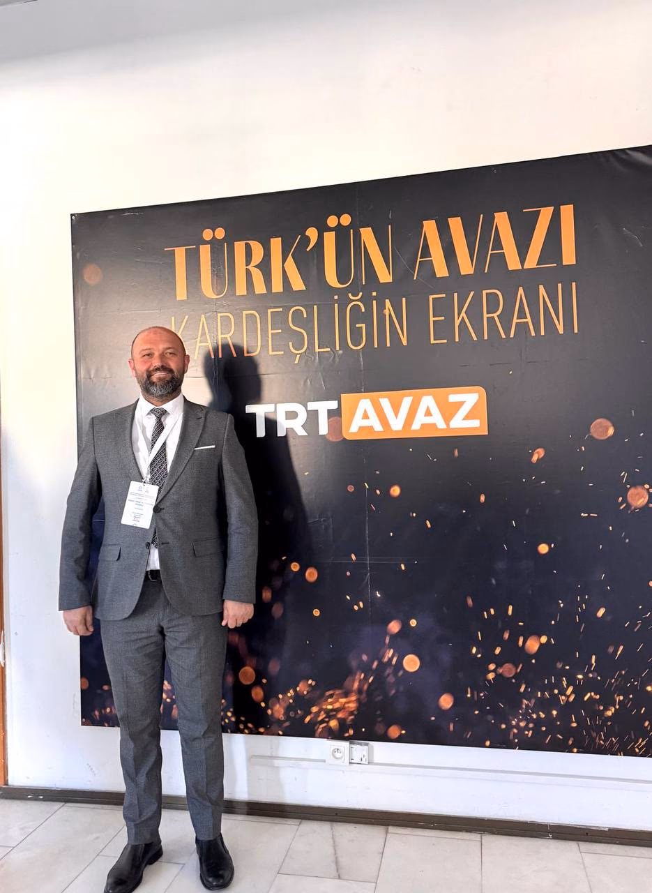 Doç. Dr. Muharrem Özdemir, TRT AVAZ 'Türk'ün Avazı' afişi önünde
