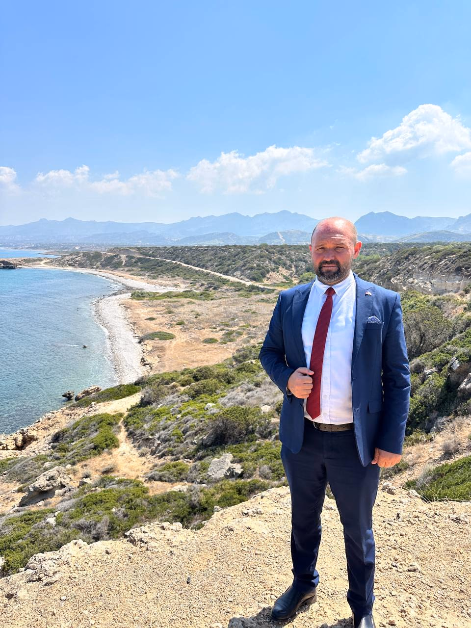 Doç. Dr. Muharrem Özdemir, Tatlısu sahil falezlerinde — arkada koy ve Beşparmak Dağları