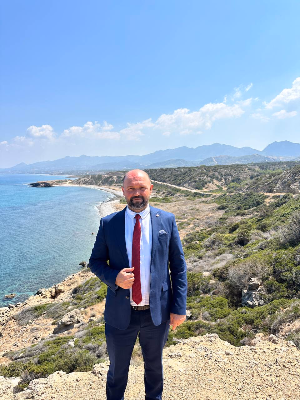 Doç. Dr. Muharrem Özdemir, makilik falez sırtında — arkada Tatlısu kıyısı