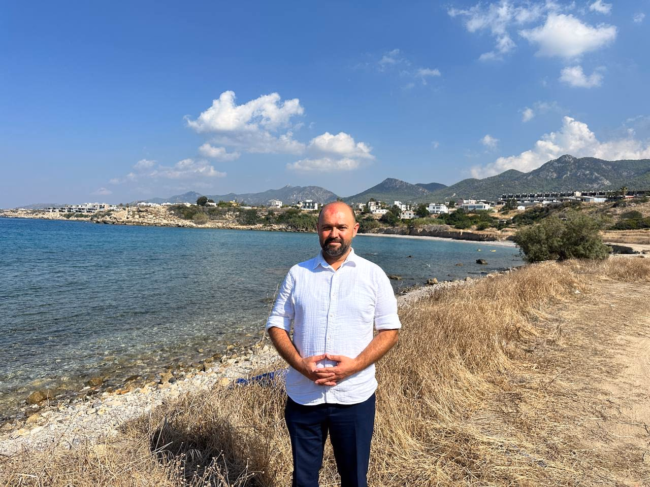 Doç. Dr. Muharrem Özdemir, Küçükerenköy koyunda — çakıl plaj ve dağ silsilesi